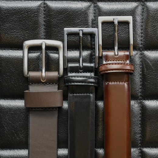 The image features three belt styles lying flat on a black leather surface. Shop the Men’s Accessories category now. 