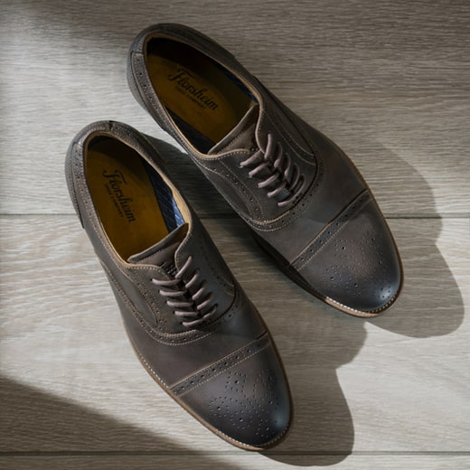 The image features an overhead shot of brown Men’s dress shoes on a white floor. Shop the Men’s Dress Shoes category now. 