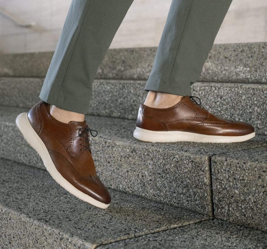 Florsheim Hybrids featuring the Dash wingtip in cognac walking up the stairs.