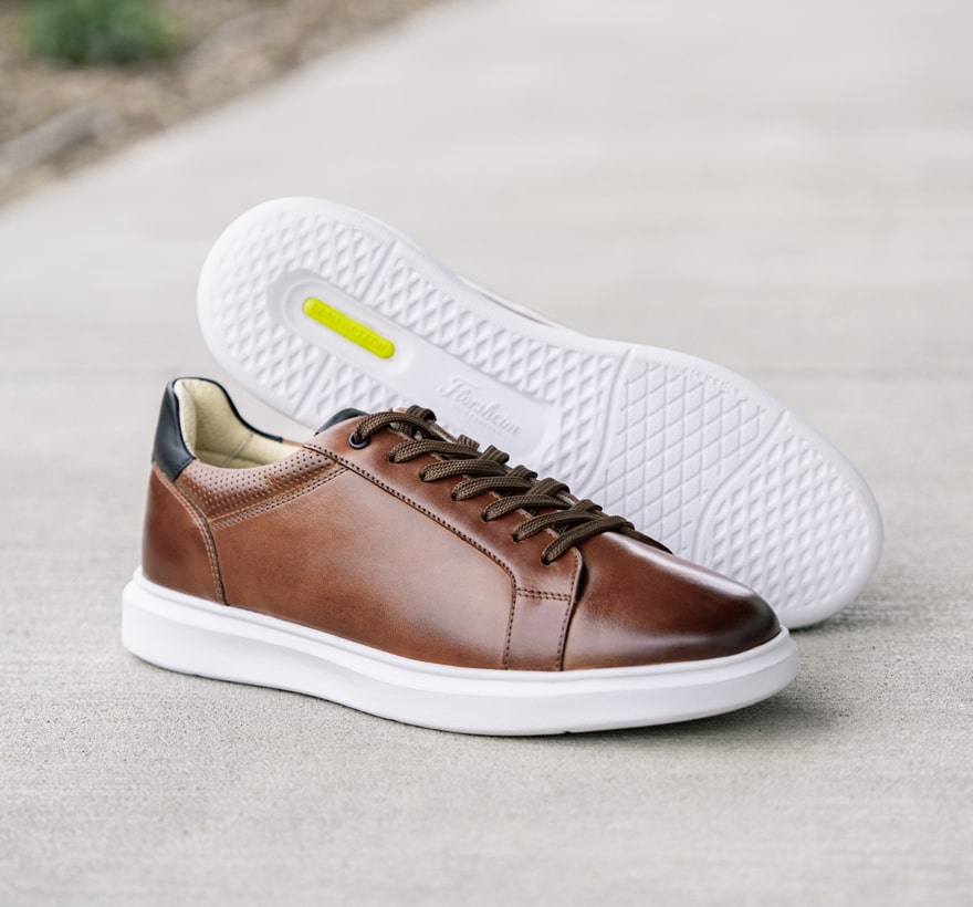 Florsheim sneakers featuring the Social plain toe lace up in cognac on a sidewalk.
